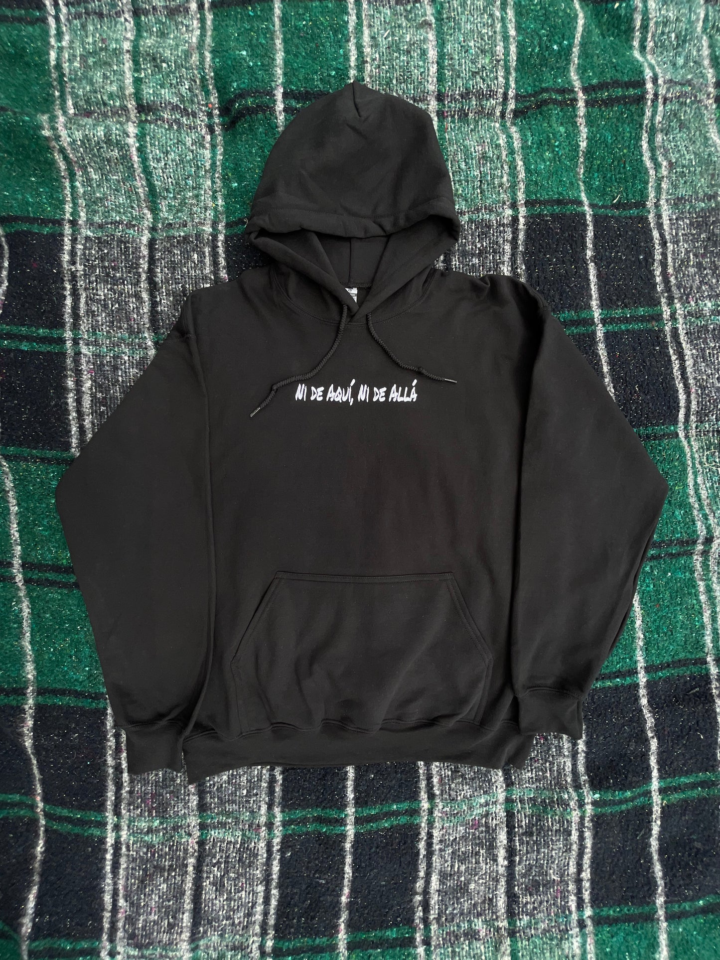 Black hoodie with text on a green and black plaid background